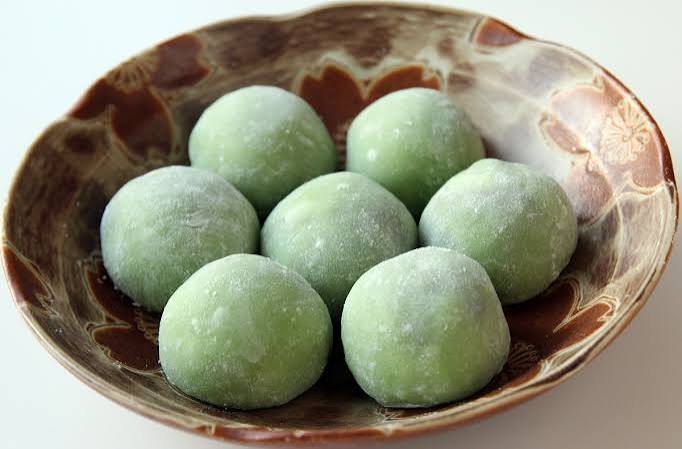 Zeven lichtgroene yomogi mochi in een aardewerken schaal