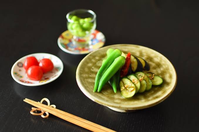 Ingelegde groenten op een schaaltje: okra, aubergine, komkommer en kerstomaat