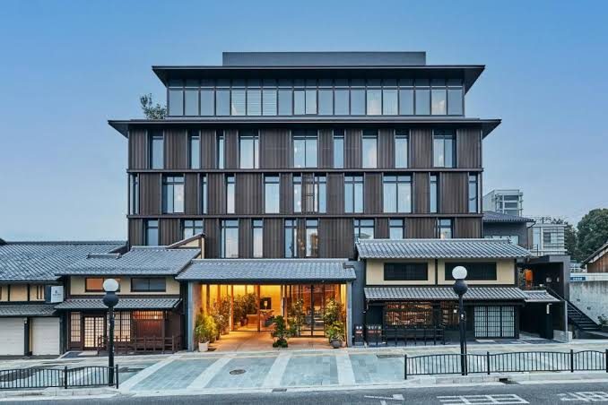 De gevel van het Nohga hotel, met de oude huizen met pannendak ernaast