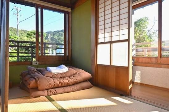 Een kamer met tatami en een futon, met uitzicht op de bergen