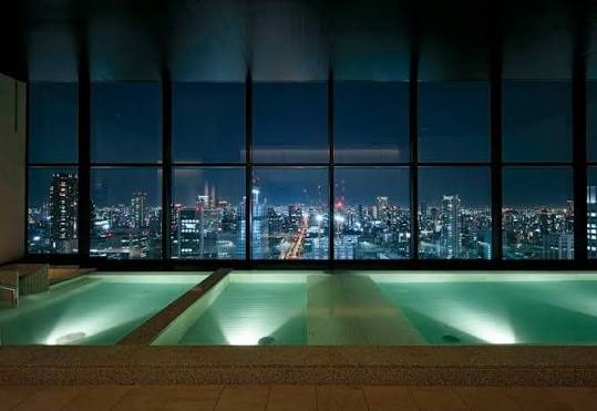 Het bad op het dak, met de lichten van Osaka achter het glas