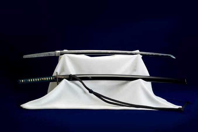 Een katana met zijn schede op een wit doek, tegen een donkerblauwe achtergrond